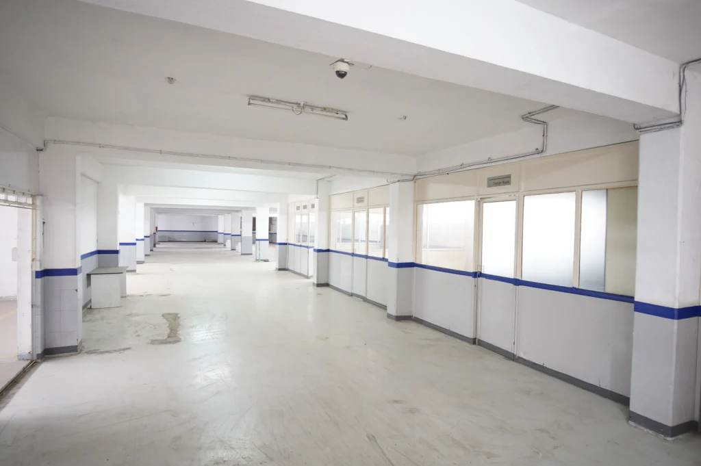 Bright industrial corridor with blue-accented walls and glass-paneled change rooms in a clean warehouse interior RCC Warehouses in Pune.